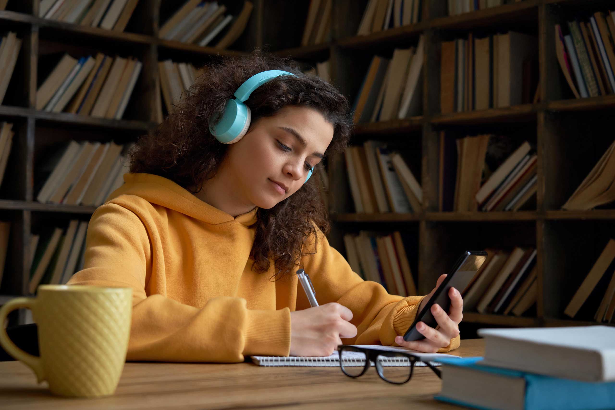 Young girl studyingin library with headphones on
